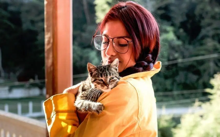 a cat lover lady with red hair embracing her tiger cat