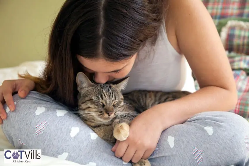 girl kissing her senior cat that suddenly became clingy