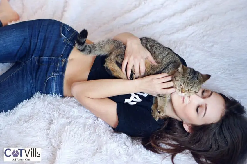 lady cuddling her cat on the bed