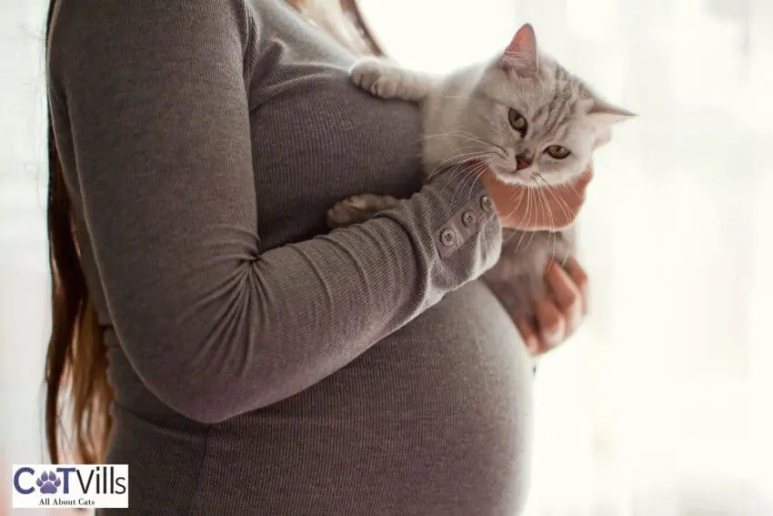 a pregnant woman holding her cat